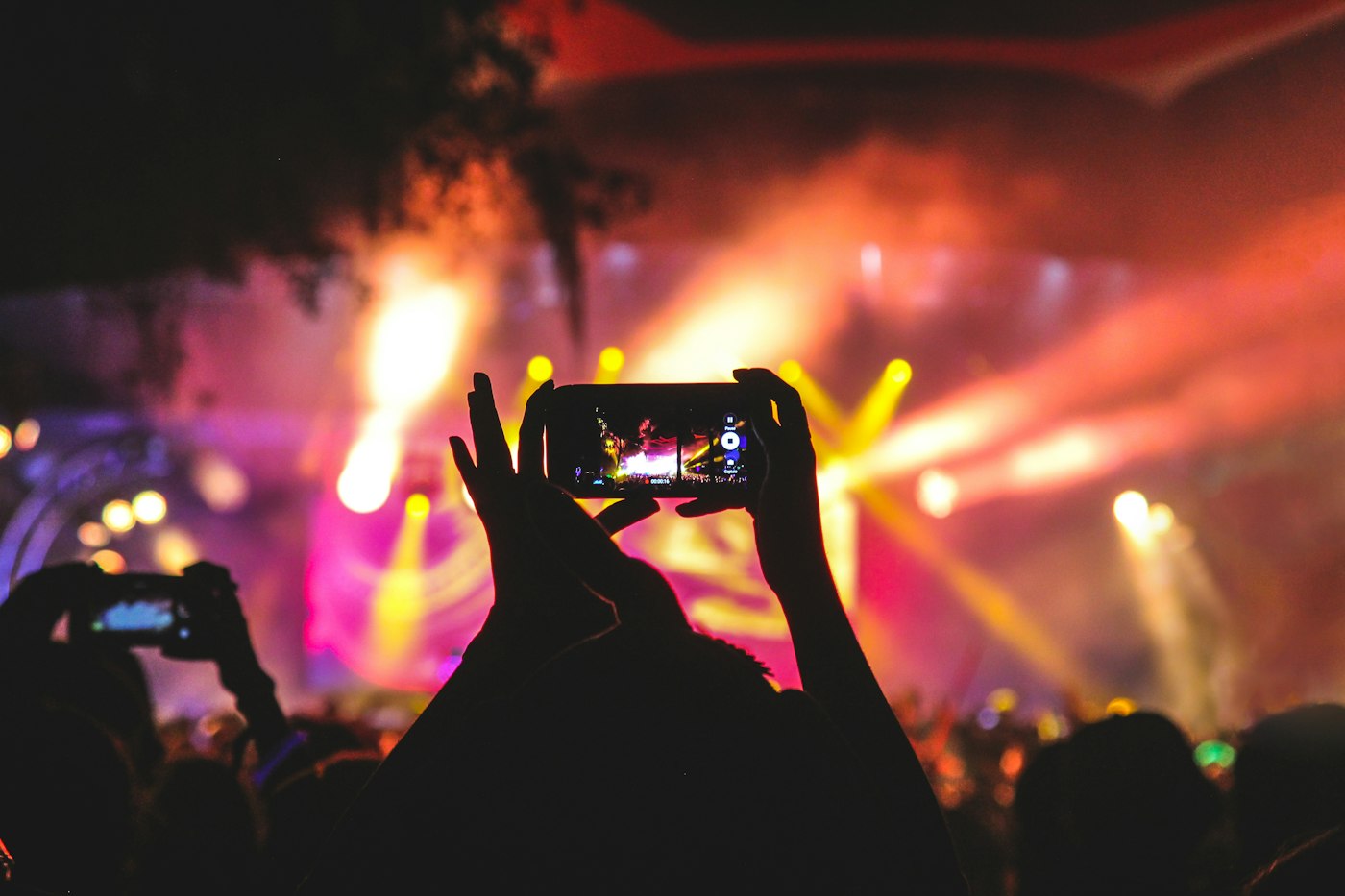 A crowd at a live show, holding a phone toward the stage